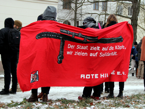 Menschen halten ein Tansparent mit der Aufschrift »Der Staat ziehlt auf die Köpfen, wir zielen auf Solidariät! Rote Hilfe e.V.«