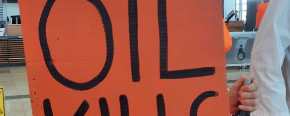 Eine Aktivistin der Letzten Generation hält ein Schild auf dem "oil kills" steht