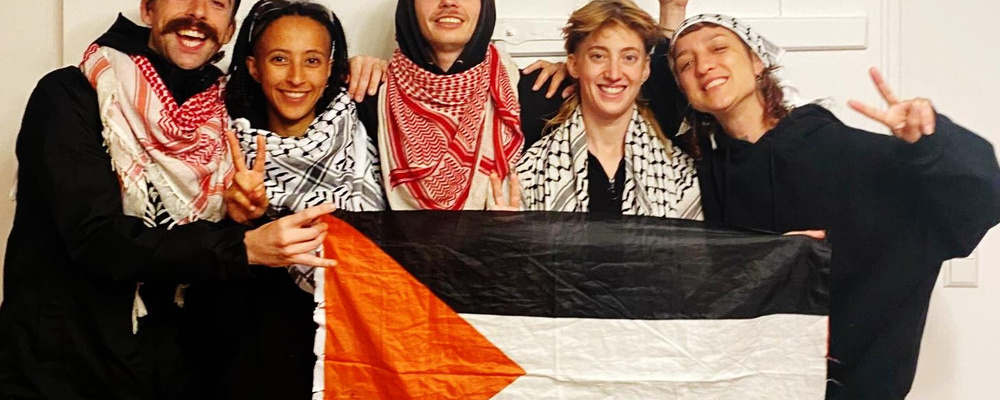 Man sieht ein Gruppenfoto der sogenannten Ulm5. Fünf Aktivist*innen, die eine Palästinaflagge halten.