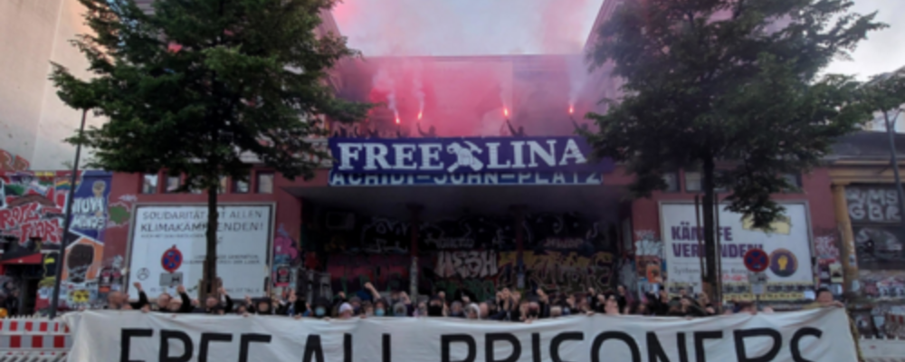 Eine Menge an Aktivist*innen findet sich zu einem Solifoto zusammen und hält Banner mit "Free Lina" & "Free All Prisioners"