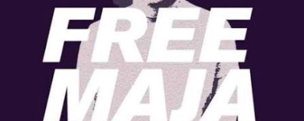 Auf dem Logo mit dunkel violettem Hintergrund sieht man die Silhouette von Maja T., davor die aufschrift "Free Maja"