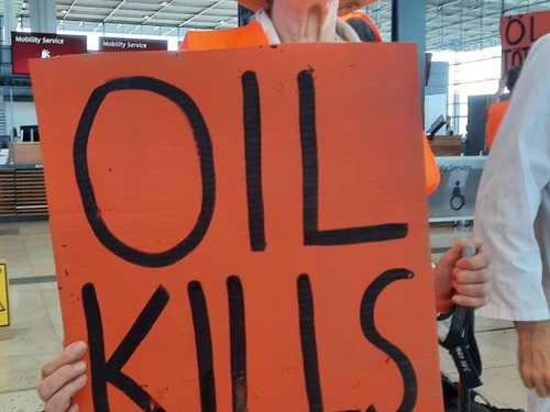 Eine Aktivistin der Letzten Generation hält ein Schild auf dem "oil kills" steht